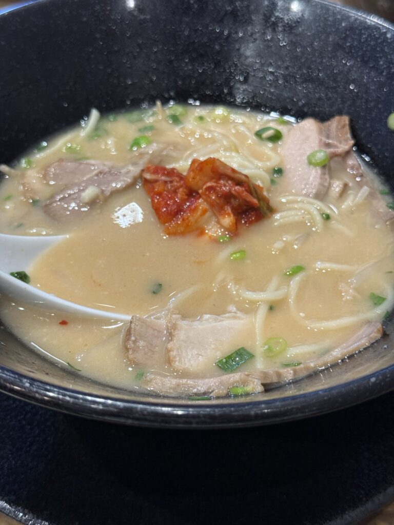 トッピングの白菜キムチをラーメンにのせた写真。